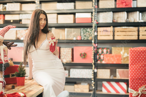 Inside a vibrant gift shop, a young woman in a lovely white dress holds a handcrafted ornament, surrounded by colorful gift boxes and holiday decorations, capturing the essence of celebration