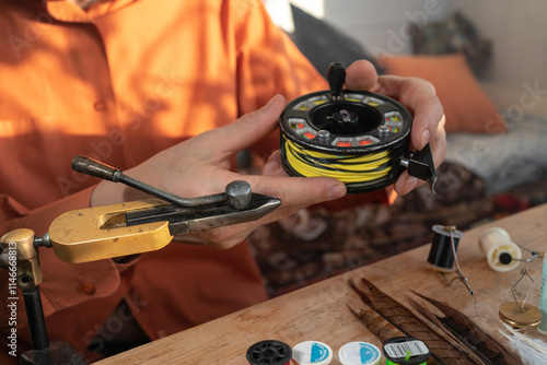 A fly fishing reel in the hands of a fly tyer.