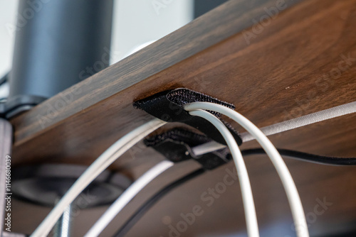Foto cable management under wooden desk using black velcro straps, showcasing organiz