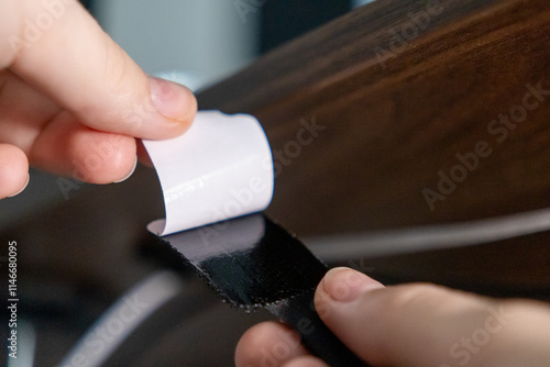 Tablou pe pânză hand peeling adhesive backing from velcro strap to secure it under wooden desk f