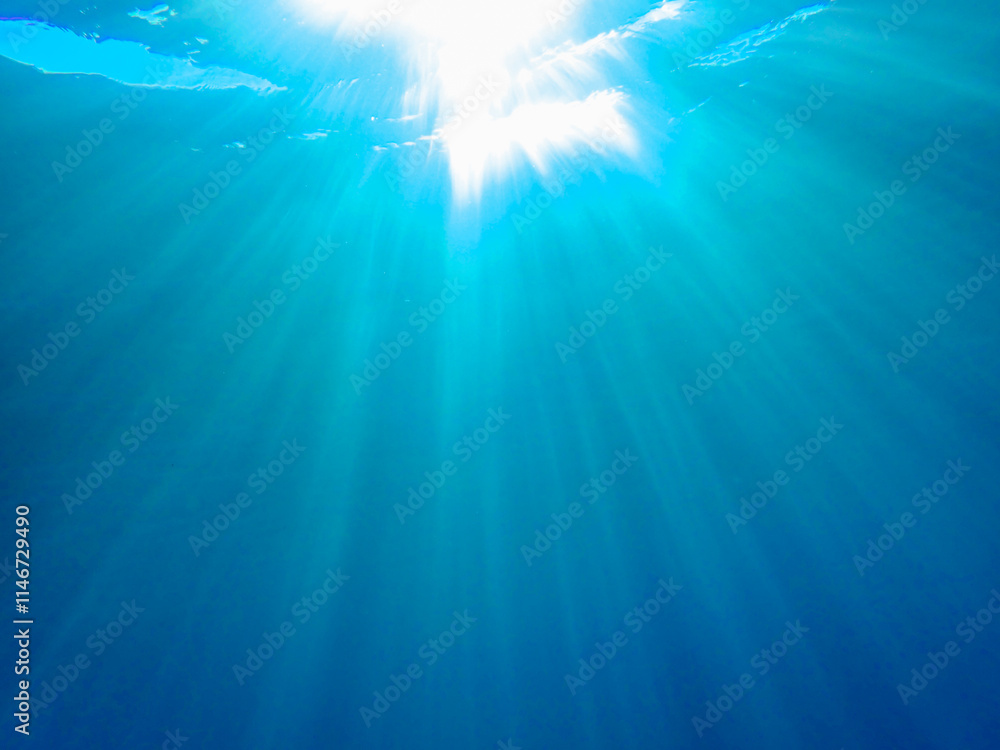 Dark blue ocean surface seen from underwater. Abstract waves underwater and rays of sunlight shining through, Sun light rays undersea deep, Underwater background with sea bottom, Mediterranean sea. Dark blue ocean surface seen from underwater. Abstract waves underwater and rays of sunlight shining through, Sun light rays undersea deep, Underwater background with sea bottom, Mediterranean sea.