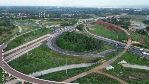 Aerial view of winding roads and green landscapes captured from above during daylight hours. Cipularang toll road infrastructure. 