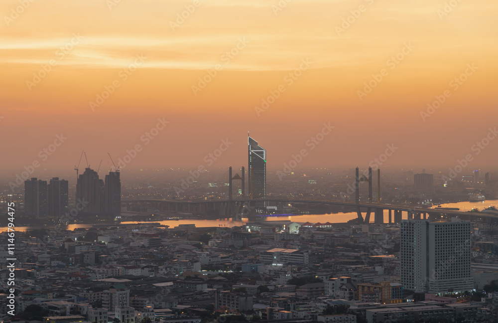 Cityscape of Bangkok with Thotsamarachan Bridge (Rama IX Bridge) crossing Chao phraya river with Dramatic orange sky background in the sundown. use it as your Wallpaper, Poster and Space for text,