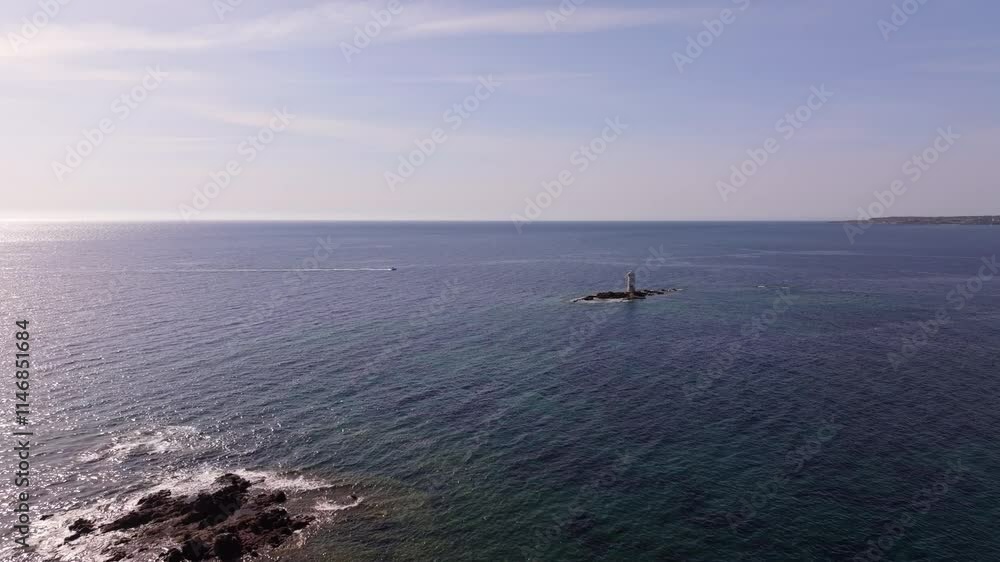 Sardinia’s Faro Mangiabarche, a beacon of resilience, rests on rocky shores. Drone footage captures calm seas, soft waves, and sunlight illuminating this scenic coastal treasure. Sardinia’s Faro Mangiabarche, a beacon of resilience, rests on rocky shores. Drone footage captures calm seas, soft waves, and sunlight illuminating this scenic coastal treasure.