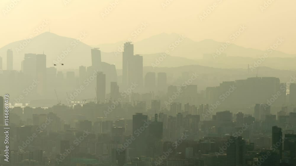 Cinematic view of Seoul in dramatic haze. City buildings and hills in background form faded layers transitioning from dark to light due to backlight of setting sun. Cinematic view of Seoul in dramatic haze. City buildings and hills in background form faded layers transitioning from dark to light due to backlight of setting sun.