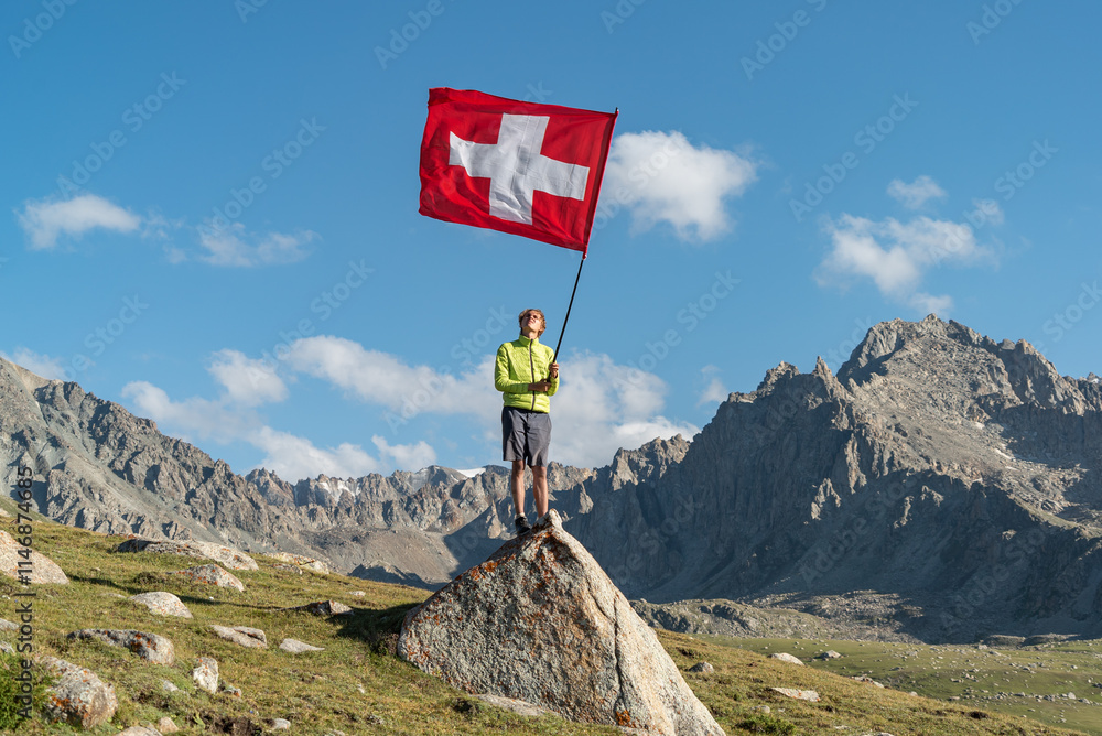 Obraz premium Hiker Man waving an Switzerland flag. The tourist reached the summit.