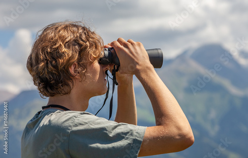 Hiker looking through binoculars on the mountain.
Traveler young man looking through binoculars outdoor.