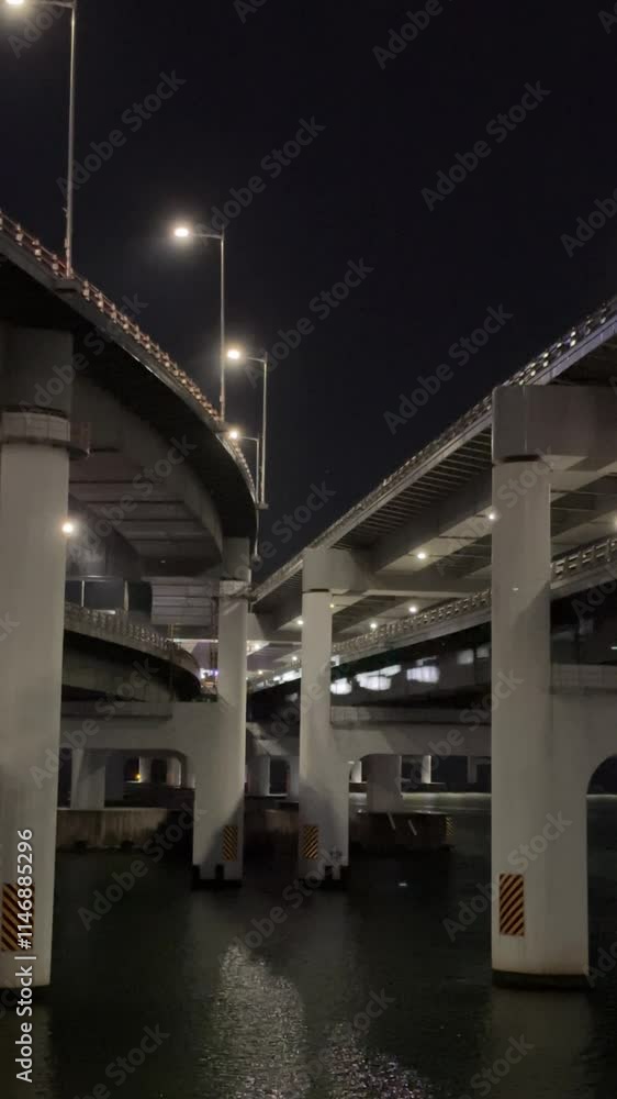 Industrial urban view at night between highway overpasses with flickering lights and reflections of passing cars, Busan, South Korea Industrial urban view at night between highway overpasses with flickering lights and reflections of passing cars, Busan, South Korea