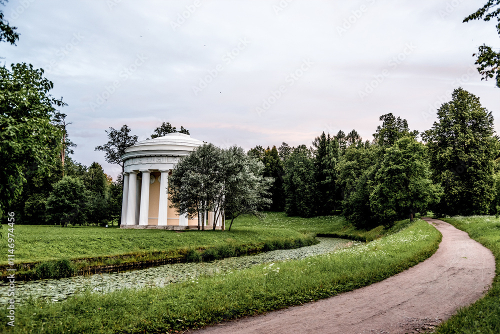 Green city park with walking path, trail next to decorative building, cloudy day Green city park with walking path, trail next to decorative building, cloudy day