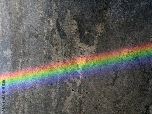 A vibrant rainbow reflection on a dark gray marble floor, showcasing the interplay of light and texture. This close-up captures the colorful gradient and natural patterns in the stone.