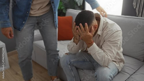Two men in a living room as one man consoles the other who has his face in his hands showcasing support and empathy in a homely environment