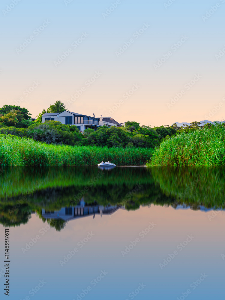 Scenic view of houses along the riverbank with water reflections in Stanford, Western Cape, South Africa