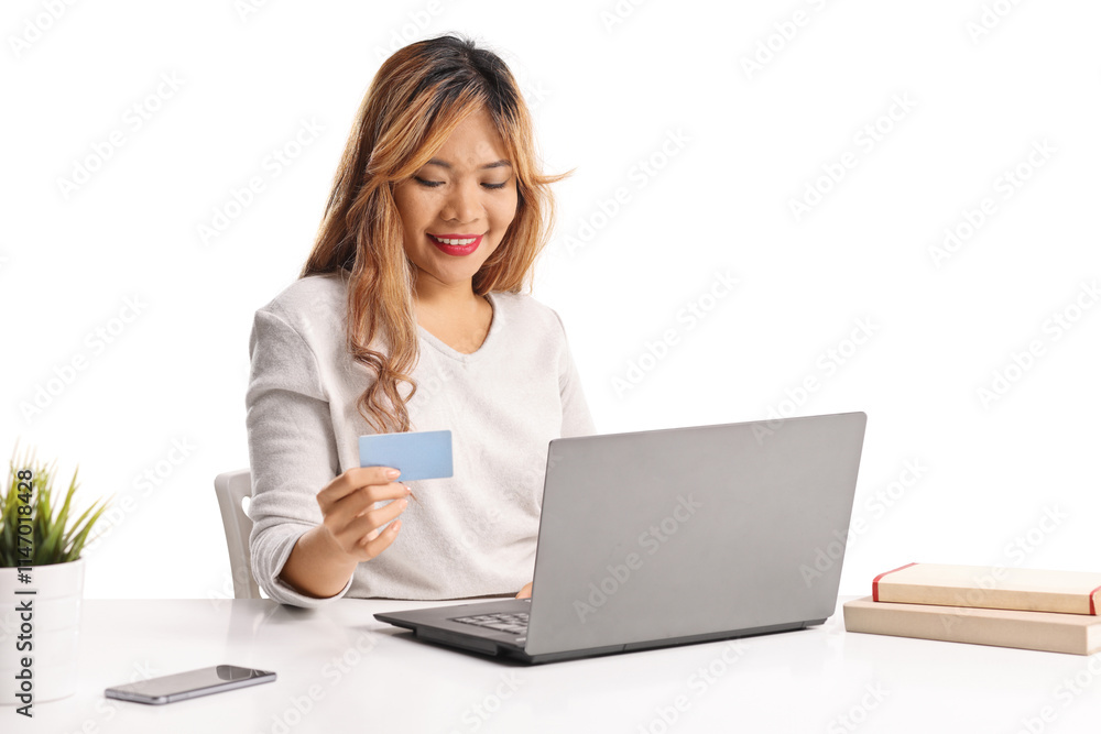 Asian woman using a credit card in front of a laptop computer Asian woman using a credit card in front of a laptop computer