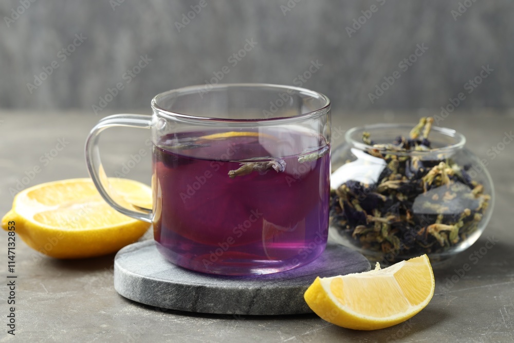 Obraz premium Delicious butterfly pea flower tea with lemon on gray textured table
