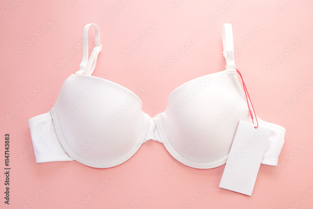 White women's bra with white paper label on pink background White women's bra with white paper label on pink background