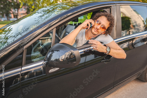 Man with curly hair using phone and looking in the rearview mirror photo