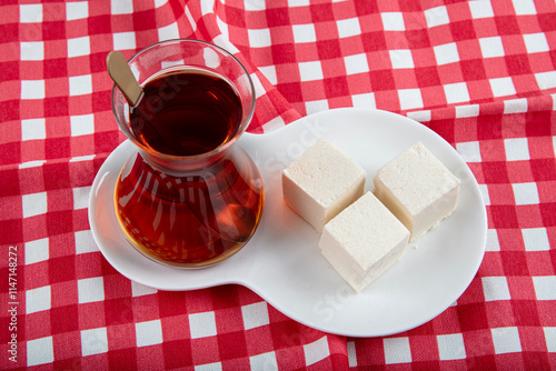 Turkish Traditional Kastamonu Cekme Helva Pismaniye. Halva on a black plate and served with a glass of tea. photo