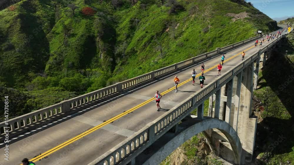 Big Sur marathon race as runners cross famous Rocky Creek bridge. Waving to the camera. Big Sur marathon race as runners cross famous Rocky Creek bridge. Waving to the camera.