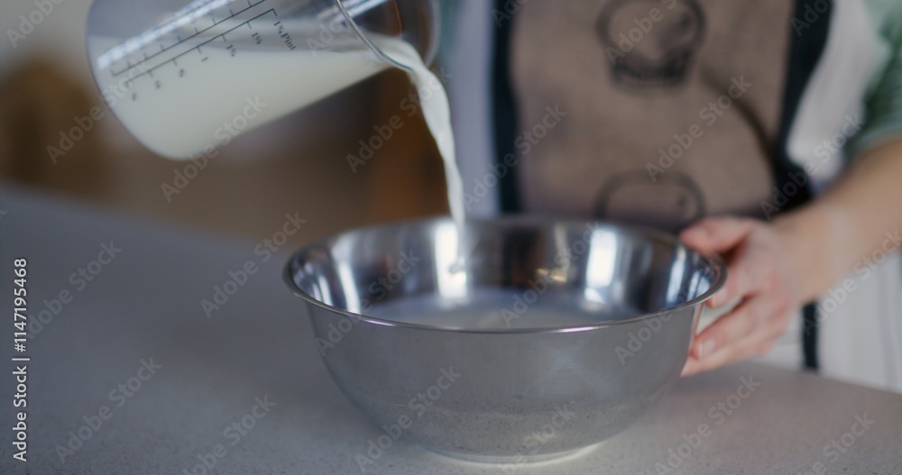 Fototapeta premium Woman Pouring Milk Into Metal Bowl and Making Dough
