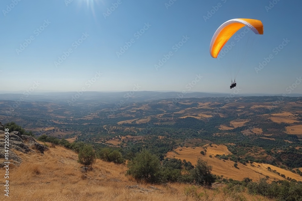 A paraglider soaring over a scenic landscape of hills and valleys under a clear blue sky. A paraglider soaring over a scenic landscape of hills and valleys under a clear blue sky.
