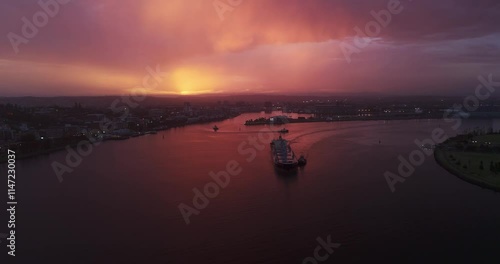 Coal Ship leaving Newcastle Harbour during sunset after storm with purple, orange sky