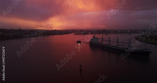 Coal Ship leaving Newcastle Harbour during sunset after storm with purple, orange sky
