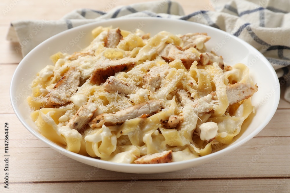 Tasty Alfredo pasta with chicken on light wooden table, closeup Tasty Alfredo pasta with chicken on light wooden table, closeup