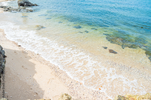 Soft blue ocean wave on clean sandy beach with rocks and splashing waves,Summer vibe on holiday vacation. photo