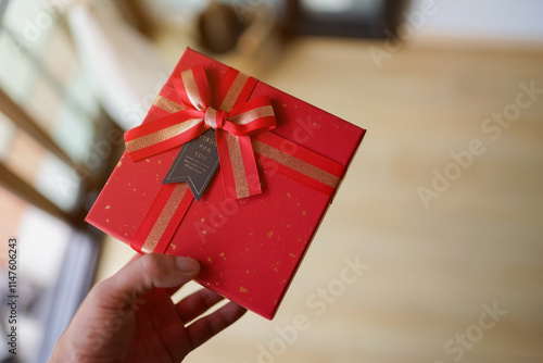 A woman holding a decorated gift box with a ribbon and bow, symbolizing celebration and giving during a holiday or special occasion photo