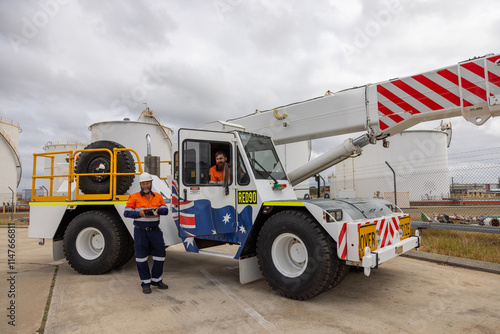 Male workman standing beside a pick and carry crane photo