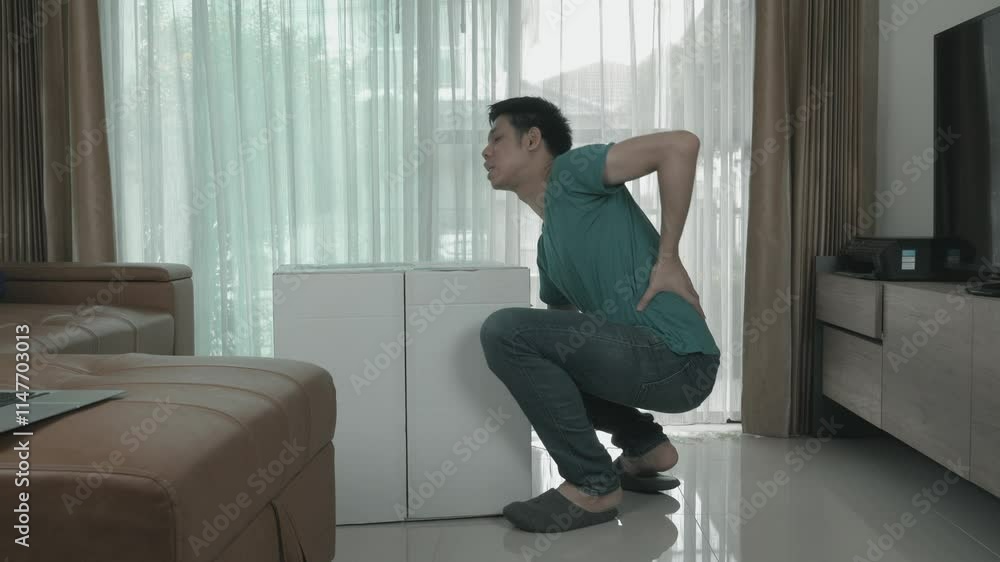 A man is lifting a white box onto a sofa. Scene is lighthearted and playful, as the man is bending over to lift the box A man is lifting a white box onto a sofa. Scene is lighthearted and playful, as the man is bending over to lift the box