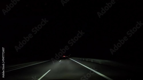 Driving on a two-lane road at night in darkness. View is from inside the car, with headlights illuminating the road ahead.