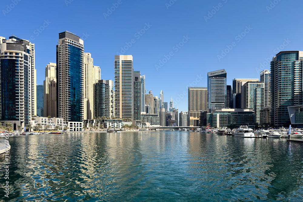 Luxury Dubai Marina skyscrapers, boat and promenade in beautiful summer day, Dubai, United Arab Emirates Luxury Dubai Marina skyscrapers, boat and promenade in beautiful summer day, Dubai, United Arab Emirates