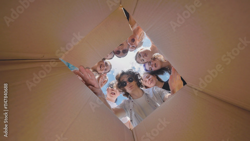 Photos High school students peering into a large cardboard box, showing excitement and