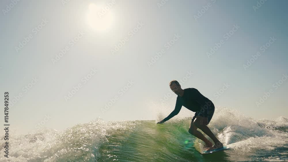 A wakeboarder performs exciting tricks on his board, moving quickly through the water. The footage shows smooth turns, jumps and acrobatics, highlighting the athlete's skill and endurance. Ideal for t A wakeboarder performs exciting tricks on his board, moving quickly through the water. The footage shows smooth turns, jumps and acrobatics, highlighting the athlete's skill and endurance. Ideal for t