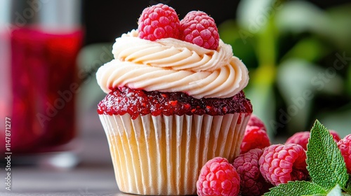 A sweet vanilla cupcake filled with tangy raspberry preserves and topped with a fluffy raspberry infused buttercream frosting photo