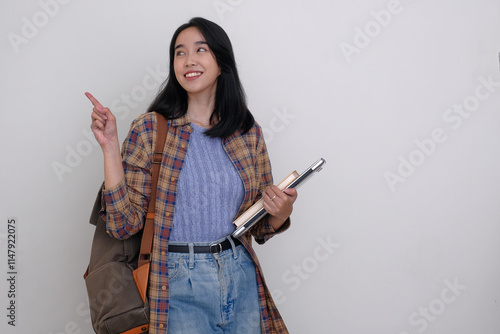 Asian female student carrying backpack and laptop computer getting ready to go to college photo