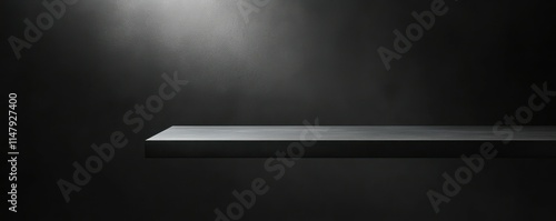 A dark grey table with soft light shining from the right side, set against an allblack background photo