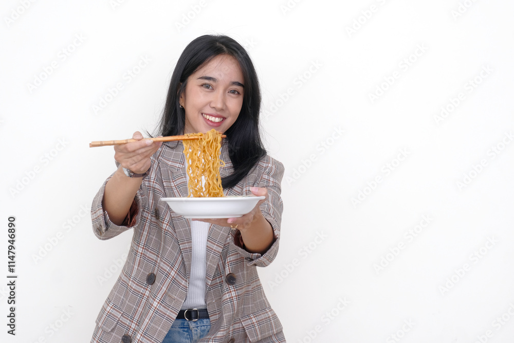 Asian young woman holding a bowl of fried noodles in one hand while using chopsticks on the other Asian young woman holding a bowl of fried noodles in one hand while using chopsticks on the other
