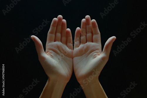 two hands extends an open palm on a black background, studio light.