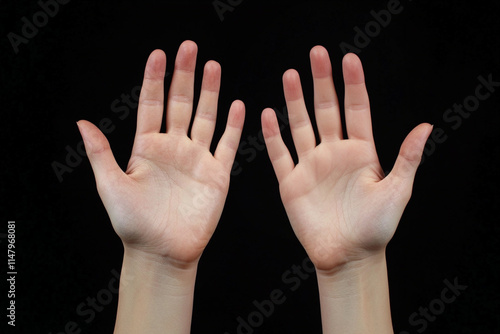 two hands extends an open palm on a black background, studio light.