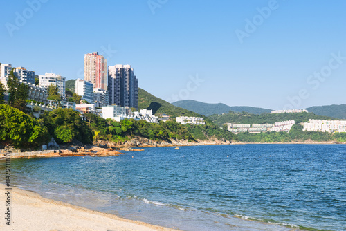 Hong Kong, China - December 18, 2024: Rocky sea shore and small sandy beach of Stanley Bay in Hong Kong. Beautiful scenic landscape with water, mountains, rocks and buildings. Just before sunset. photo