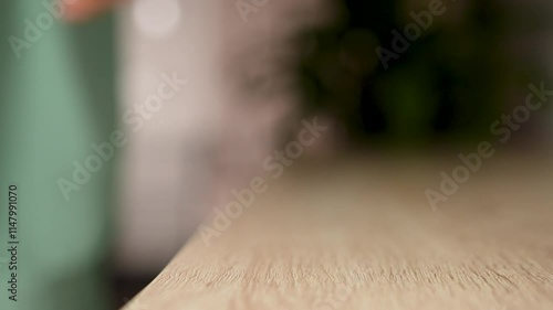 Woman hand puts mobile phone on wooden desk, close-up. Putting down cellphone on wooden table