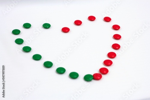 Heart shape made of green and red circular candies on a clean white background, symbolizing love, harmony, and festive themes