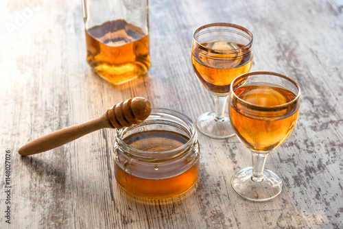 Fototapeta Still life close-up of two glasses of honey mead (medovukha) with honey dipper o