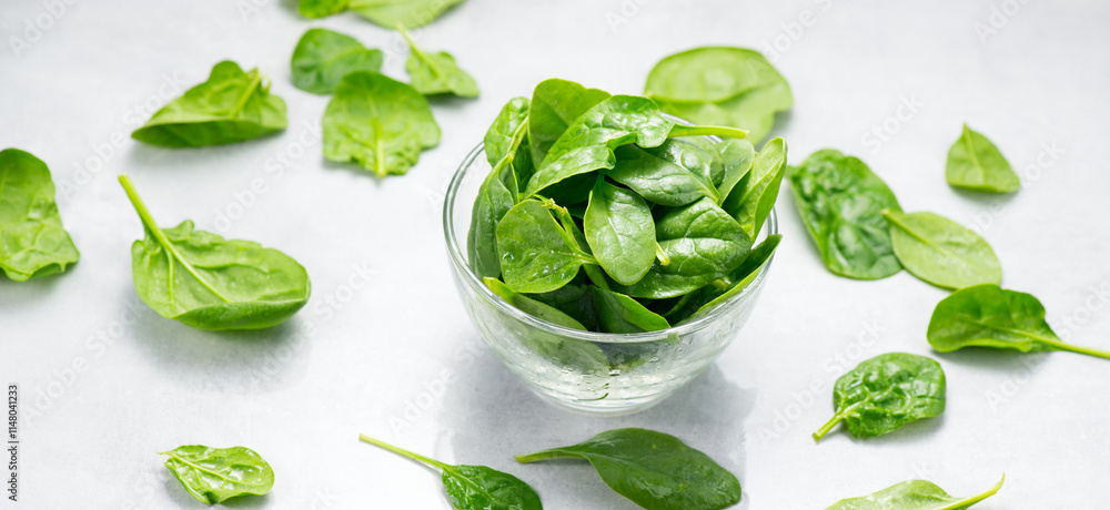 Obraz premium Spinach leaves in a transparent glass bowl isolated on white background. Heap of Baby spinach fresh leaves close up, Healthy vegan food, diet, dieting 