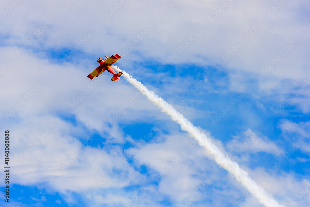 A red and white plane is flying through the sky with a trail of smoke behind it A red and white plane is flying through the sky with a trail of smoke behind it