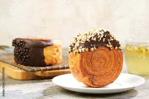 Delicious Cromboloni fusion croissants ,Round puff pastry filled with cream, topped with chocolate glaze and nuts. A perfect blend of crunchy texture and soft, creamy filling. photo