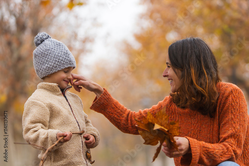 Mother playfully touching her child's nose in a park during autumn. Estilo de vida, Motherhood. photo