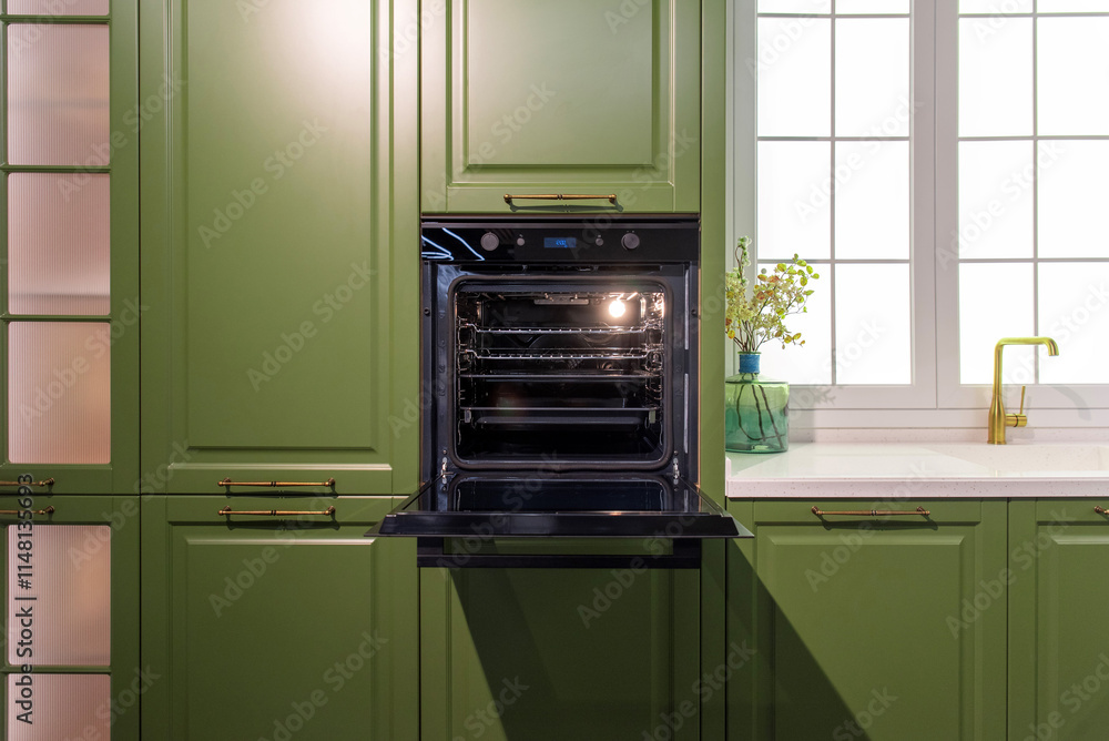 Fototapeta premium Modern black built-in oven in a green kitchen with a open door
